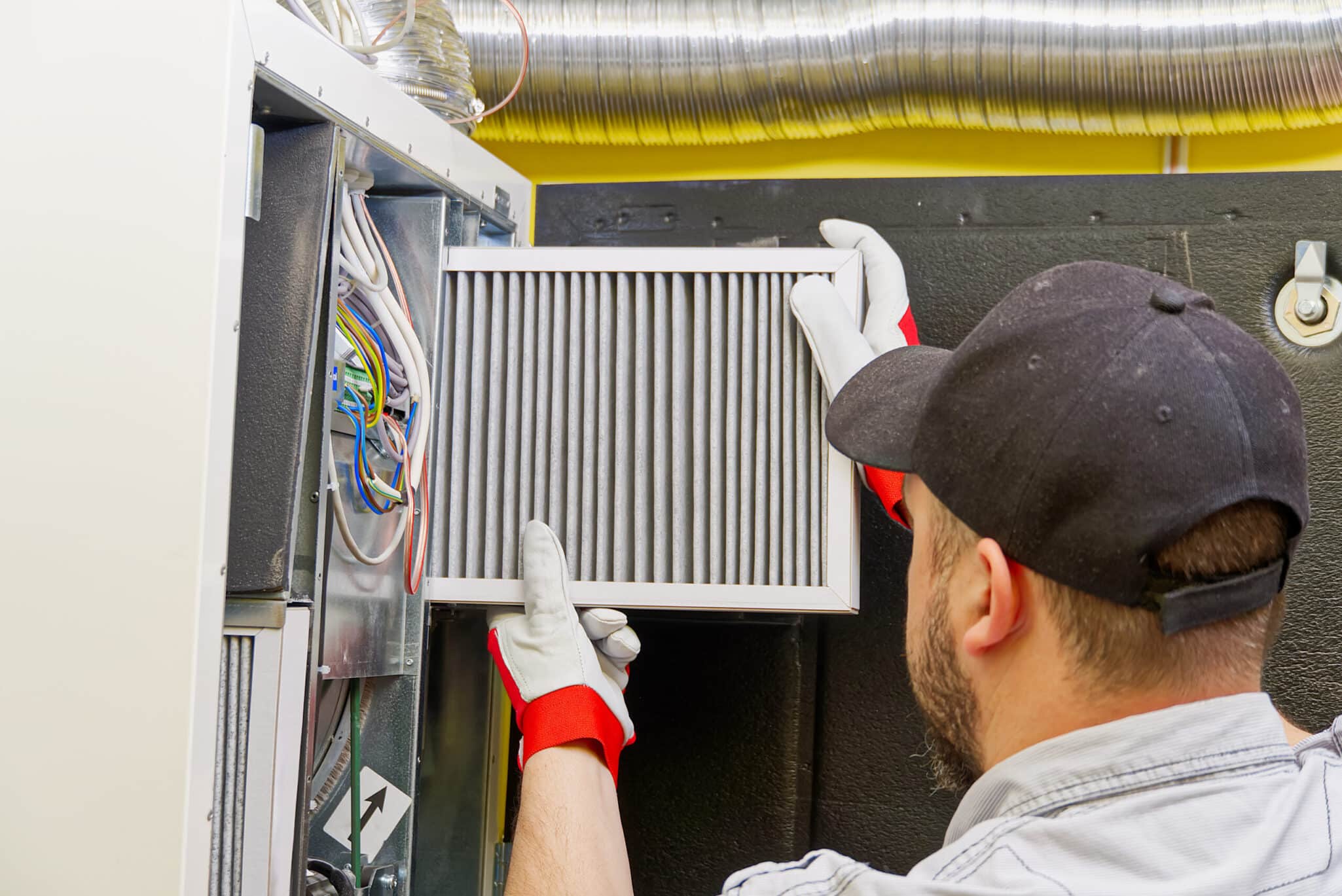 HVAC service technician changing dirty air filter in the central ventilation system