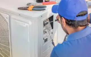 HVAC technician performing a central air conditioning maintenance inspection in a Connecticut home to ensure efficient cooling and system performance