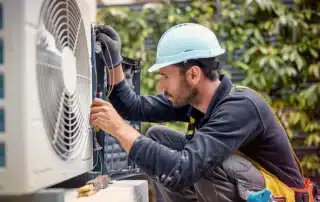 A technician installing a heat pump outside a home